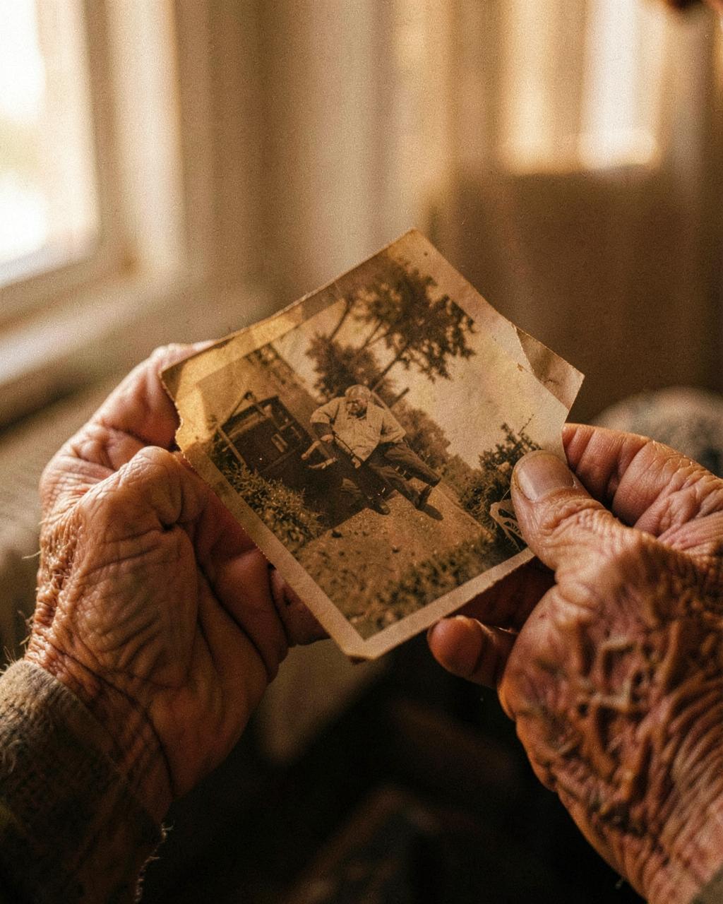 Elderly hands holding an old photograph, soft with age